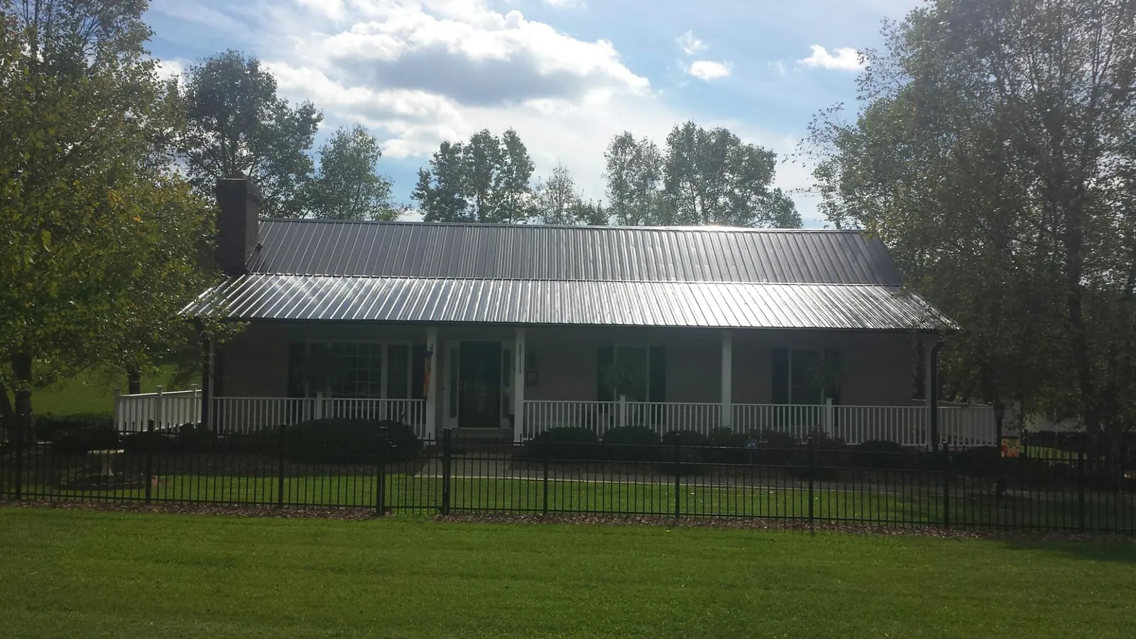 Gray metal roof on a brick ranch with a full width front porch — Gutter Guard Installation work by our crew in Youngsville